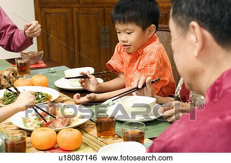 Close-up of a boy and his family at the dining table View Large Photo Image Stock Photograph - Close-up of a boy and his family at the dining table. Fotosearch
