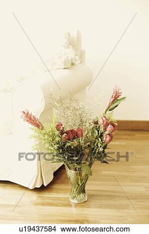 Picture - Close-up of a flower vase near an armchair on a wooden floor. Fotosearch