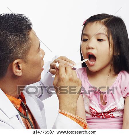 Close-up of a male doctor examining his patient with a tongue depressor View Large Photo Image Stock Photo - Close-up of a male doctor examining his patient with a tongue depressor. Fotosearch