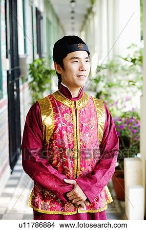 Picture - Close-up of a mid adult man in traditional clothing standing in a corridor. Fotosearch