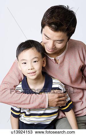 Stock Image - Close-up of a mid adult man smiling with his son. Fotosearch