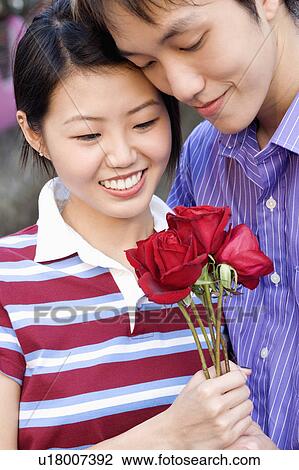 Stock Image - Close-up of a young couple holding a bunch of roses. Fotosearch