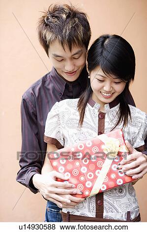 Close-up of a young couple holding a gift and smiling View Large Photo Image Stock Photo - Close-up of a young couple holding a gift and smiling. Fotosearch