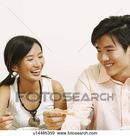 Stock Photo - Close-up of a young couple sitting and smiling. Fotosearch