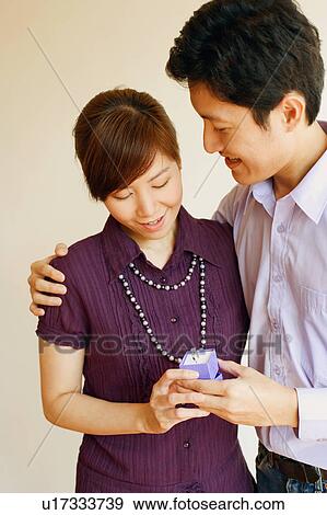 Close-up of a young couple standing together and holding a jewelry box View Large Photo Image Stock Photo - Close-up of a young couple standing together and holding a jewelry box. Fotosearch
