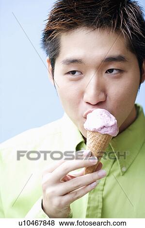 Stock Photo - Close-up of a young man eating an ice-cream cone. Fotosearch