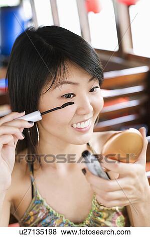 Close-up of a young woman applying mascara View Large Photo Image Stock Photo - Close-up of a young woman applying mascara. Fotosearch