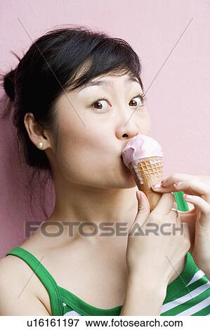 Close-up of a young woman eating an ice-cream cone View Large Photo Image Stock Photo - Close-up of a young woman eating an ice-cream cone. Fotosearch