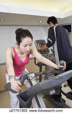 Close-up of a young woman exercising in a gym with a young man View Large Photo Image Stock Image - Close-up of a young woman exercising in a gym with a young man. Fotosearch