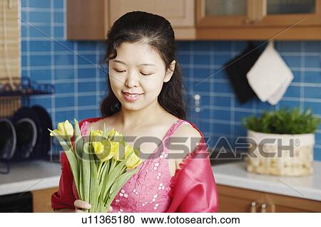 Stock Image - Close-up of a young woman holding a bunch of flowers smiling. Fotosearch