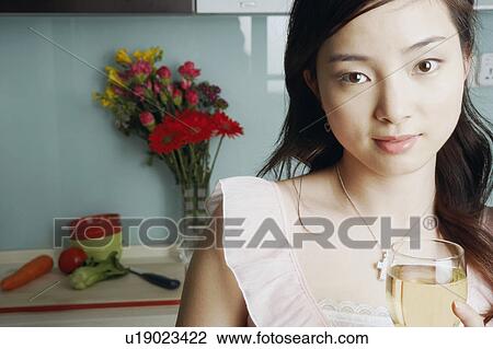 Stock Image - Close-up of a young woman holding a glass of white wine. Fotosearch