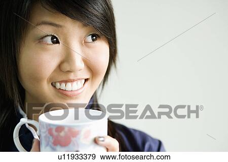 Close-up of a young woman holding a tea cup View Large Photo Image Stock Photo - Close-up of a young woman holding a tea cup. Fotosearch