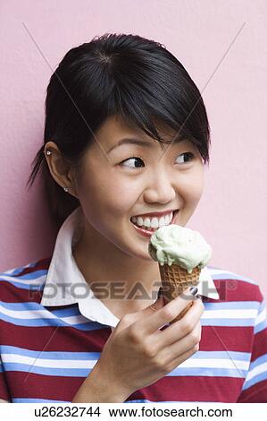 Picture - Close-up of a young woman holding an ice-cream cone. Fotosearch