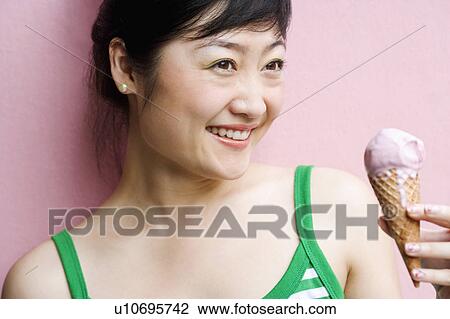 Close-up of a young woman holding an ice-cream cone View Large Photo Image Stock Image - Close-up of a young woman holding an ice-cream cone. Fotosearch