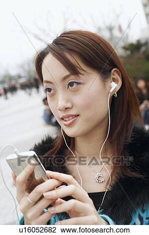 Close-up of a young woman listening to an MP3 Player View Large Photo Image Stock Image - Close-up of a young woman listening to an MP3 Player. Fotosearch