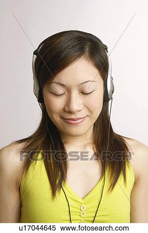 Stock Photography - Close-up of a young woman listening to music. Fotosearch