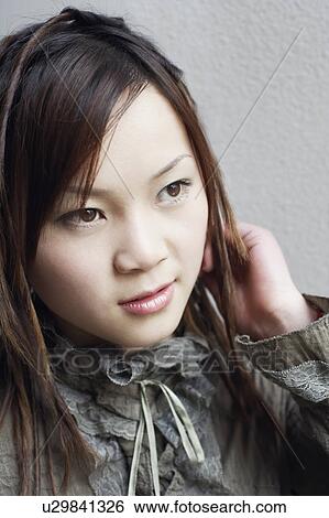 Close-up of a young woman looking away View Large Photo Image Stock Photograph - Close-up of a young woman looking away. Fotosearch