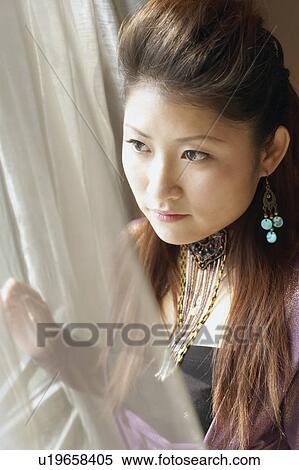 Stock Photography - Close-up of a young woman looking out of a window. Fotosearch
