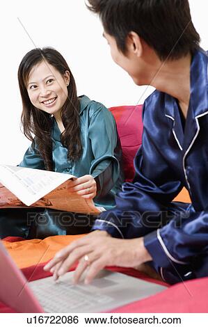 Close-up of a young woman reading newspaper and a mid adult man using a laptop View Large Photo Image Stock Photograph - Close-up of a young woman reading newspaper and a mid adult man using a laptop. Fotosearch
