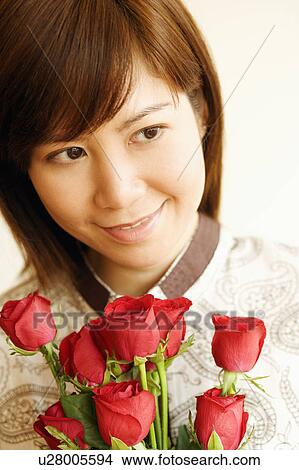 Close-up of a young woman smiling and holding a bouquet of red roses View Large Photo Image Picture - Close-up of a young woman smiling and holding a bouquet of red roses. Fotosearch