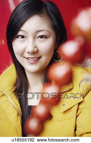 Stock Image - Close-up of a young woman smiling behind a stick of avocado's. Fotosearch