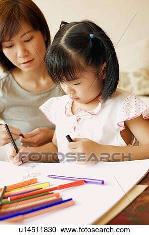 Stock Image - Close-up of a young woman teaching her daughter to color. Fotosearch