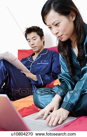 Close-up of a young woman using a laptop and mid adult man holding a newspaper View Large Photo Image Stock Image - Close-up of a young woman using a laptop and mid adult man holding a newspaper. Fotosearch