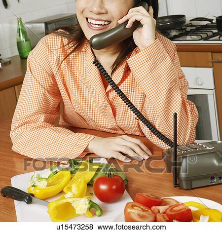 Close-up of a young woman using a telephone in the kitchen View Large Photo Image Stock Photo - Close-up of a young woman using a telephone in the kitchen. Fotosearch