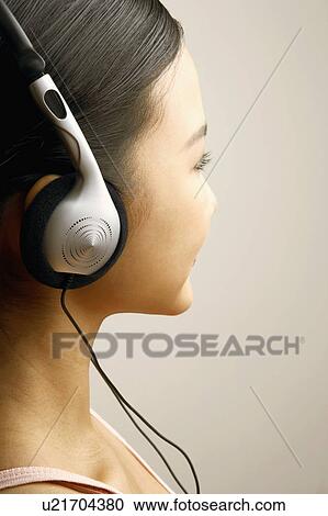 Stock Image - Close-up of a young woman wearing headphones. Fotosearch