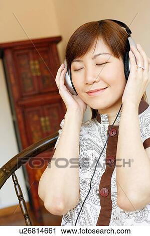 Stock Image - Close-up of a young woman wearing headphones and listening to music. Fotosearch