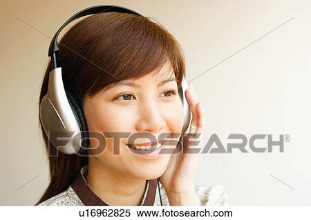 Stock Photography - Close-up of a young woman wearing headphones and listening to music. Fotosearch