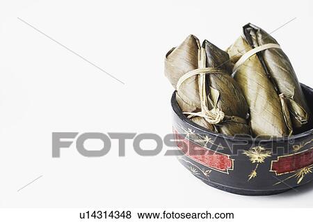 Stock Photo - Close-up of rice wrapped in banana leaves in a bowl. Fotosearch