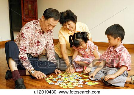 Girl and a boy playing jigsaw puzzle with their grandparents View Large Photo Image Stock Image - Girl and a boy playing jigsaw puzzle with their grandparents. Fotosearch