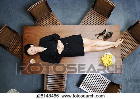 Stock Photograph - High angle view of a businesswoman lying on the table. Fotosearch