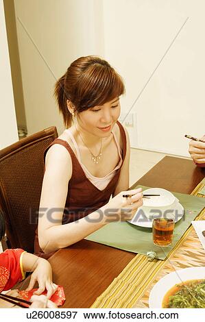 Stock Photo - High angle view of a young woman eating food. Fotosearch