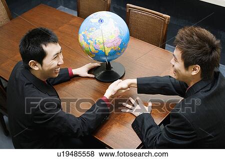 Stock Photo - High angle view of two businessmen shaking hands. Fotosearch