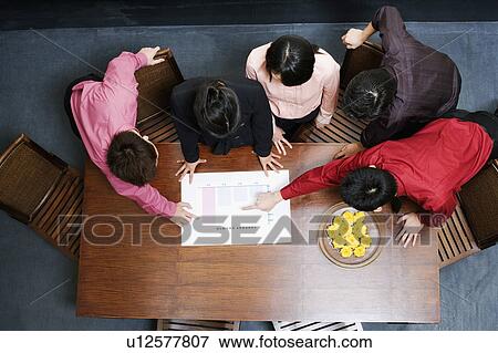 Stock Photo - High angle view of two businesswomen and three businessmen discussing a bar graph. Fotosearch