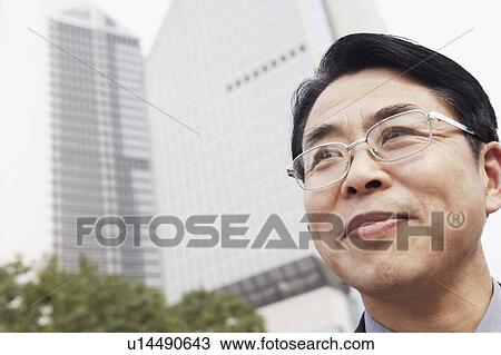 Low angle view of a businessman smiling View Large Photo Image Stock Image - Low angle view of a businessman smiling. Fotosearch