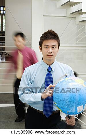 Stock Photo - Portrait of a businessman holding a globe. Fotosearch