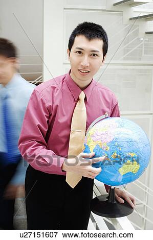 Stock Photo - Portrait of a businessman holding a globe. Fotosearch