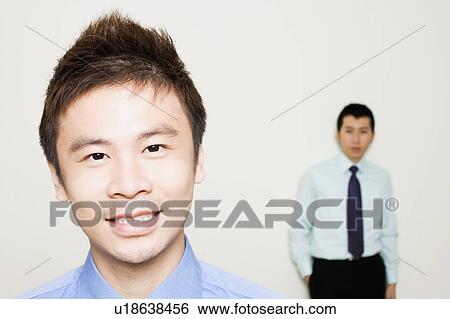 Stock Photograph - Portrait of a businessman with another standing behind him. Fotosearch