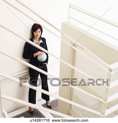 Stock Photograph - Portrait of a businesswoman holding a globe and posing. Fotosearch