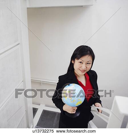 Stock Photography - Portrait of a businesswoman holding a globe and smiling. Fotosearch