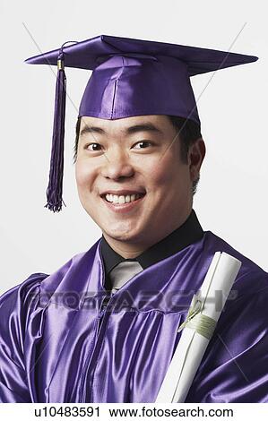 Stock Image - Portrait of a male graduate holding a diploma. Fotosearch