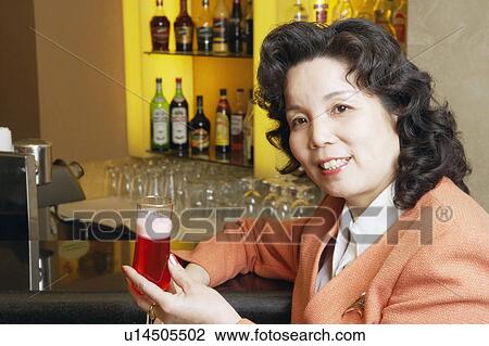Stock Image - Portrait of a mature woman holding a glass. Fotosearch