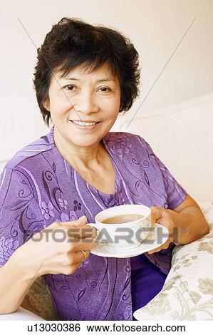 Portrait of a mature woman holding a cup of tea View Large Photo Image Stock Photograph - Portrait of a mature woman holding a cup of tea. Fotosearch
