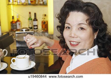 Portrait of a mature woman stirring a cup of coffee View Large Photo Image Picture - Portrait of a mature woman stirring a cup of coffee. Fotosearch