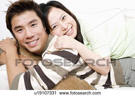 Portrait of a mid adult man and a young woman lying on a couch View Large Photo Image Stock Image - Portrait of a mid adult man and a young woman lying on a couch. Fotosearch