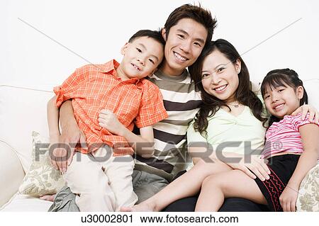 Portrait of a mid adult man and a young woman sitting on a couch with their son and daughter View Large Photo Image Stock Image - Portrait of a mid adult man and a young woman sitting on a couch with their son and daughter. Fotosearch