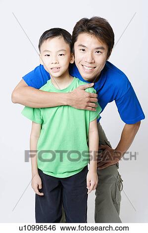 Portrait of a mid adult man hugging his son from behind View Large Photo Image Stock Photograph - Portrait of a mid adult man hugging his son from behind. Fotosearch